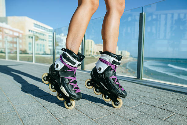 Close-up of legs in black and purple inline skates on an oceanfront path.